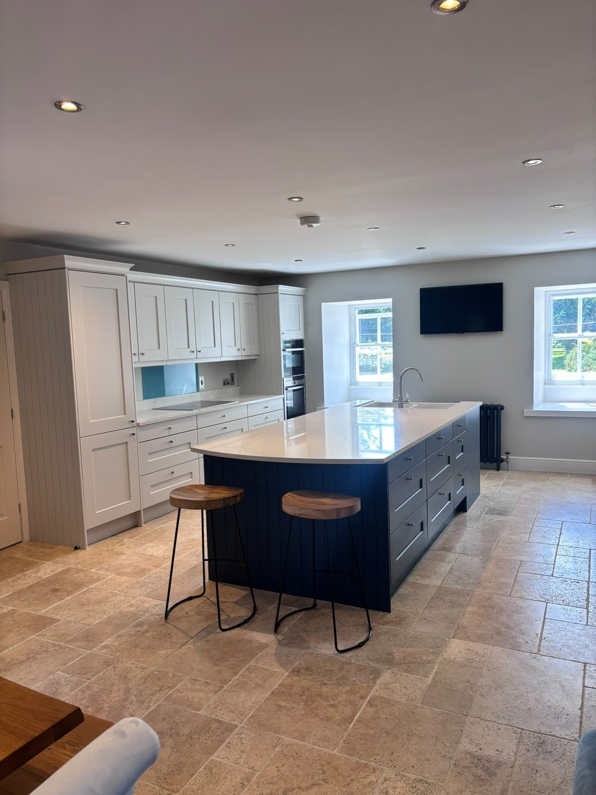 Kitchen painted soft white with a navy island