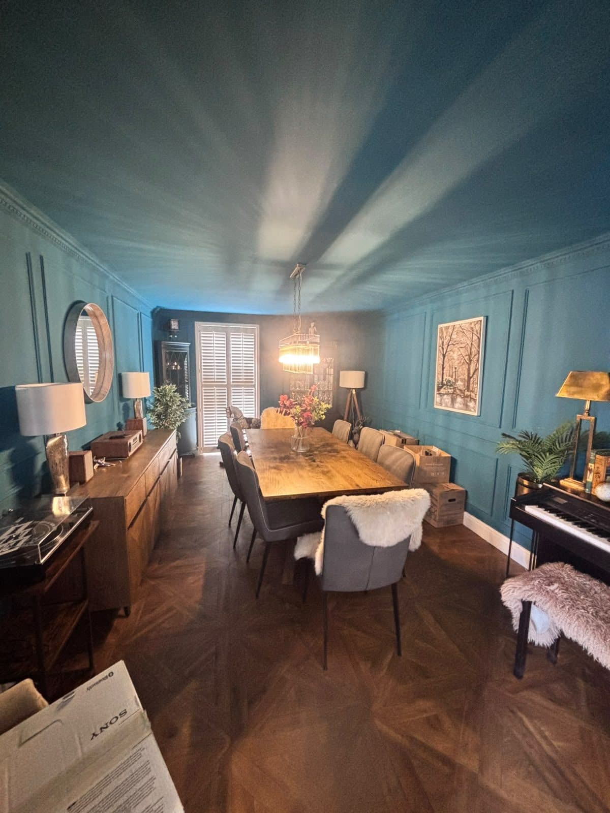 Dining room decorated in deep teal with panelled walls
